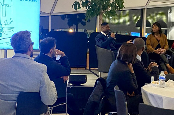 audience at a panel discussion featuring a speaker discussing topics related to community engagement and policing strategies in a contemporary setting with a focus on public safety