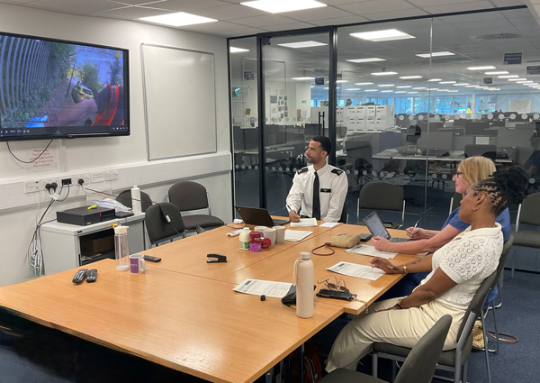 four people in a conference room watching a presentation on a screen discussing topics related to teamwork and collaboration in the workplace