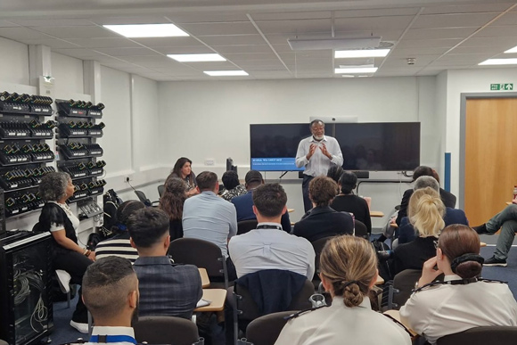 group of professionals attending a presentation in a modern meeting room with a speaker discussing topics related to leadership and development