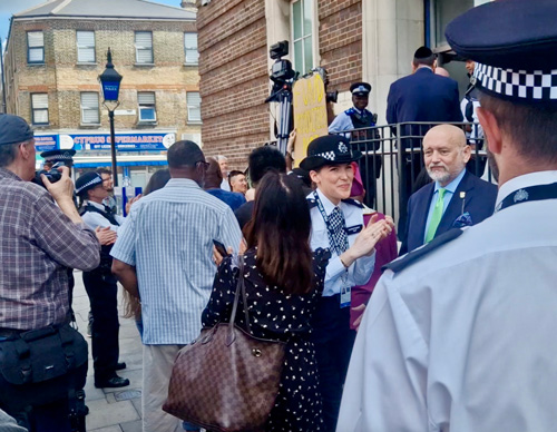 police officers and crowd outside building during event with two police uniforms and people taking photos