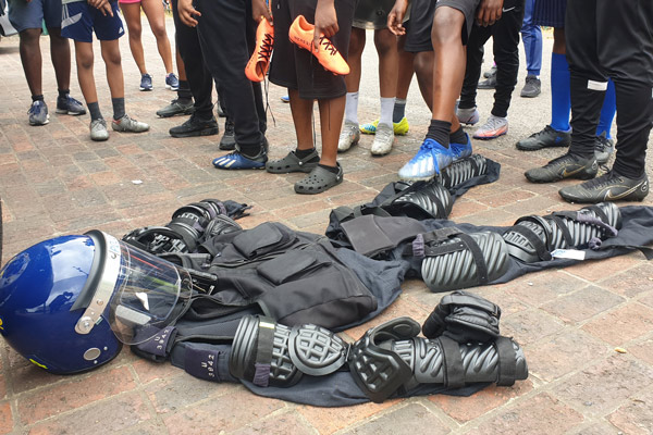 group of people gathered around protective gear laid out on the ground