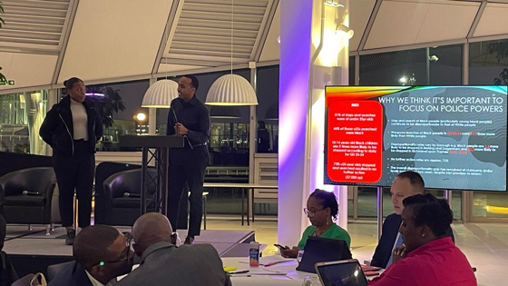 discussion about police powers with two speakers at a podium while audience observes in a modern setting